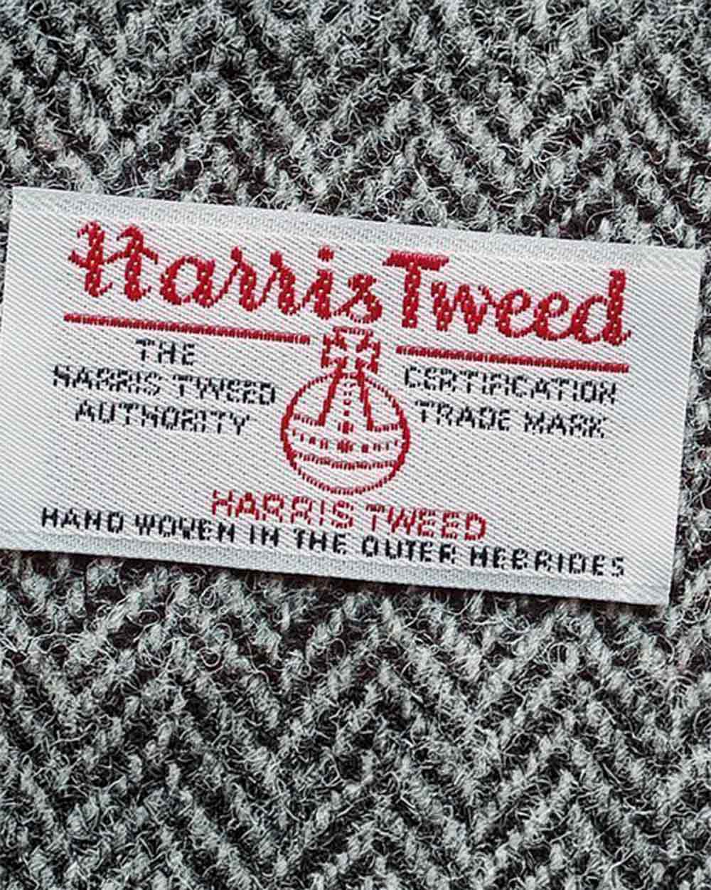 xuits-Harris Tweed Etikett auf grauem Fischgrätmuster, handgewebt auf den Äußeren Hebriden.